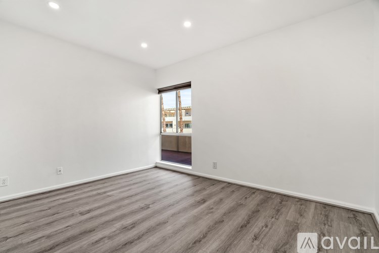 A spacious room with wooden flooring and a large window.