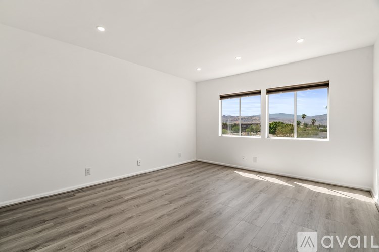 A spacious room with wooden flooring and a large window overlooking a landscape.