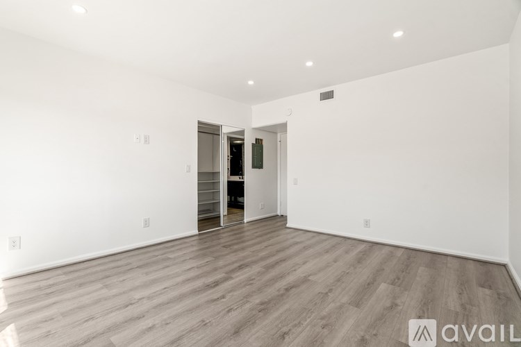 A spacious room with wooden flooring and a white wall.