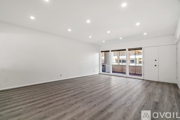 A spacious room with wooden flooring and white walls.