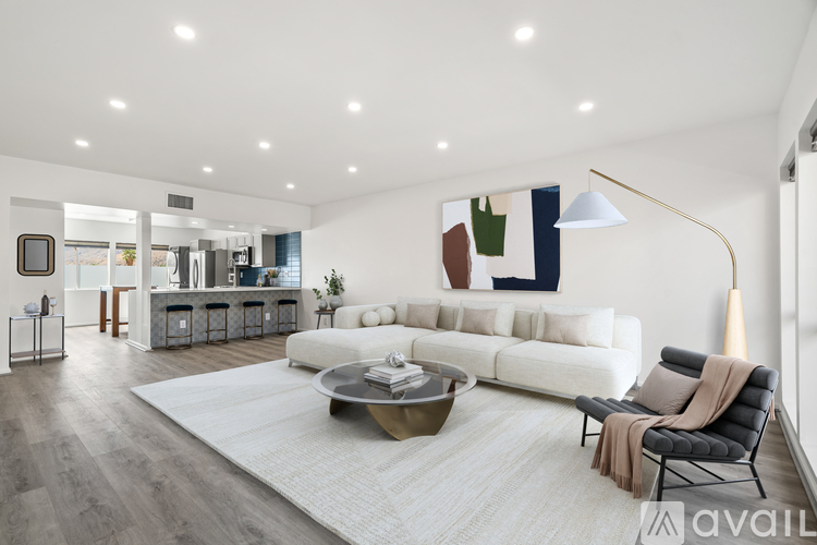 A modern living room with a white sofa, a grey armchair, and a coffee table.