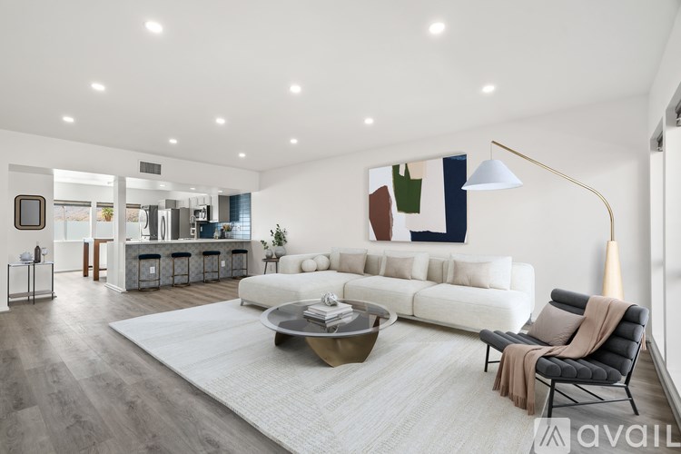 A modern living room with a white sofa, a grey armchair, and a coffee table.