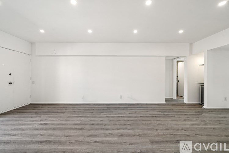 A spacious room with wooden flooring and white walls.