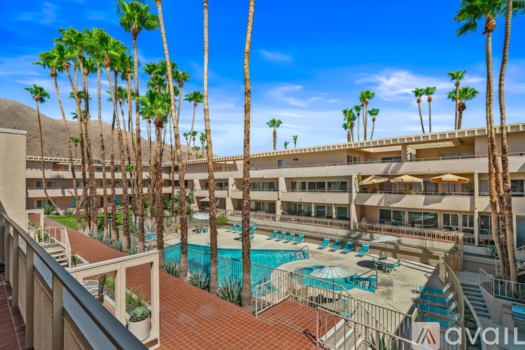 A pool surrounded by palm trees and a building in the background.