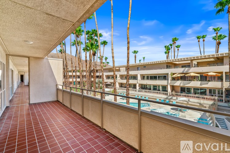 A balcony with a pool and palm trees.