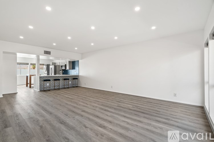 A spacious room with wooden flooring and white walls.