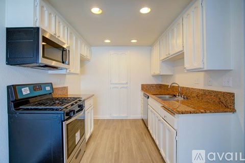 A kitchen with a black stove top oven and a granite counter top.