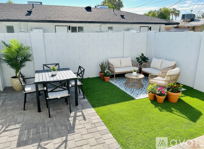 A patio with a table and chairs surrounded by a white fence.