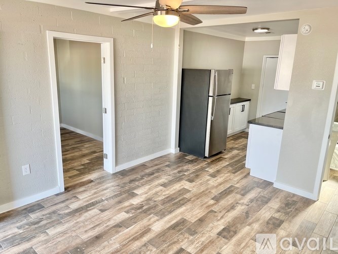 A kitchen with a refrigerator, ceiling fan, and wooden flooring.