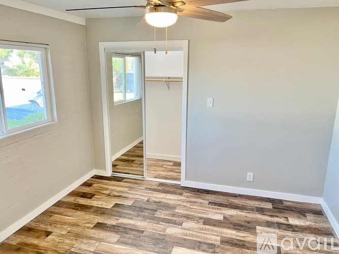 A room with a ceiling fan and wood flooring.