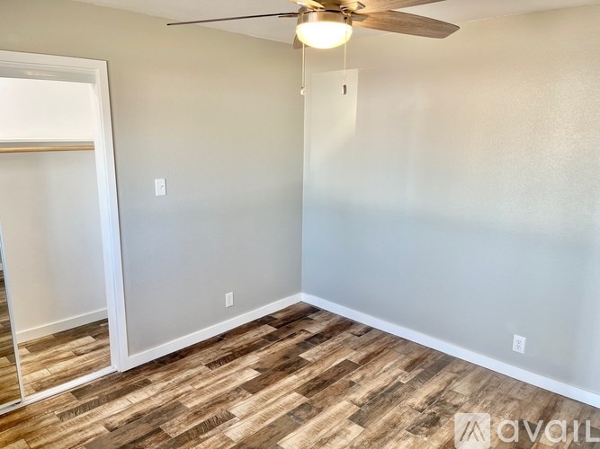 A room with a ceiling fan and wooden flooring.