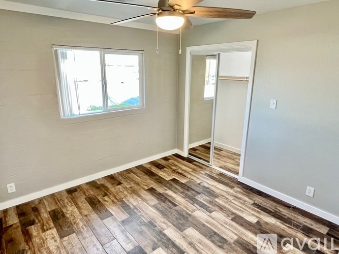A room with a ceiling fan and wooden flooring.