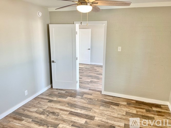 A room with a ceiling fan and a doorway leading to another room.