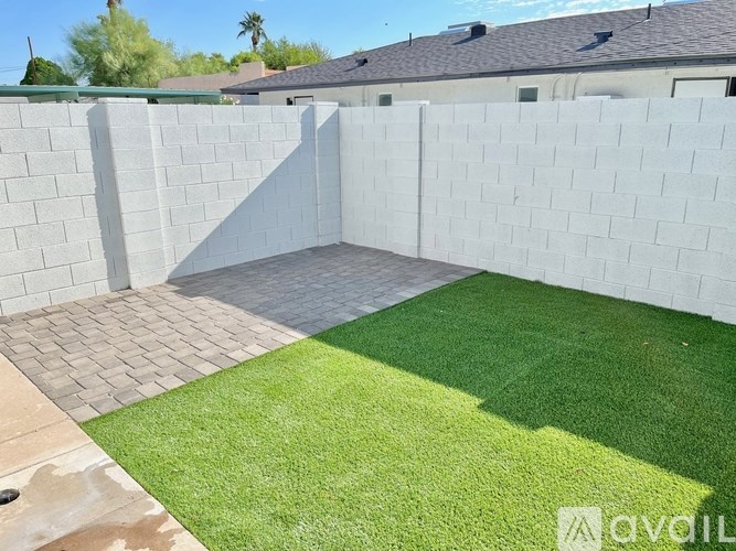 A backyard with a white fence and a green lawn.