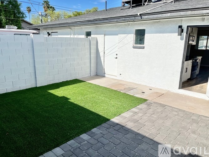 A backyard with a white fence and a green lawn.