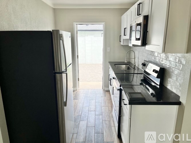 A kitchen with black appliances and white cabinets.