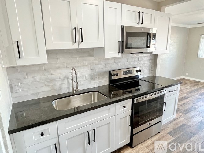 A kitchen with white cabinets and black countertops.