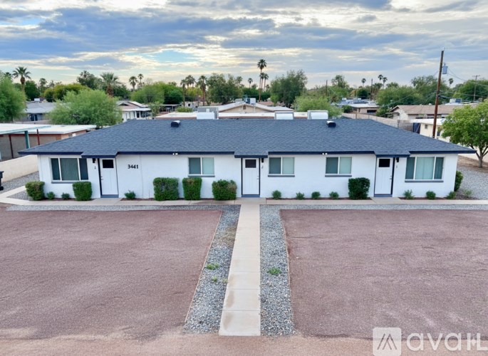 A white house with a black roof and a driveway in front.