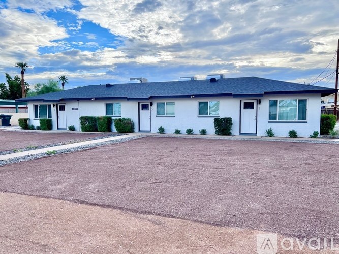 A white house with a black roof and a driveway in front.