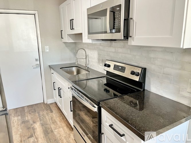 A kitchen with a black granite countertop and white cabinets.