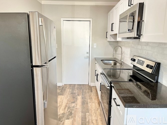 A kitchen with a black fridge and white cabinets.