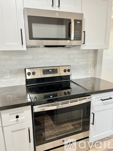 A kitchen with a black stove top oven and a silver microwave above it.