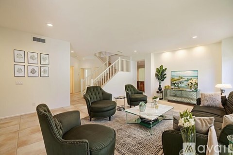 A living room with a green chair and a glass coffee table.