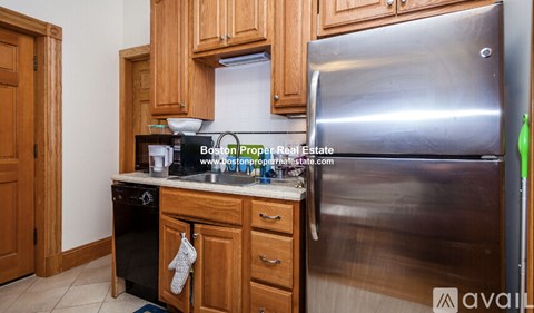 A kitchen with wooden cabinets and a stainless steel refrigerator.