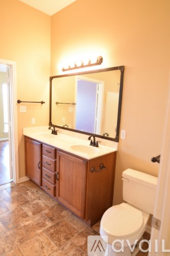 A bathroom with a toilet, sink and mirror.