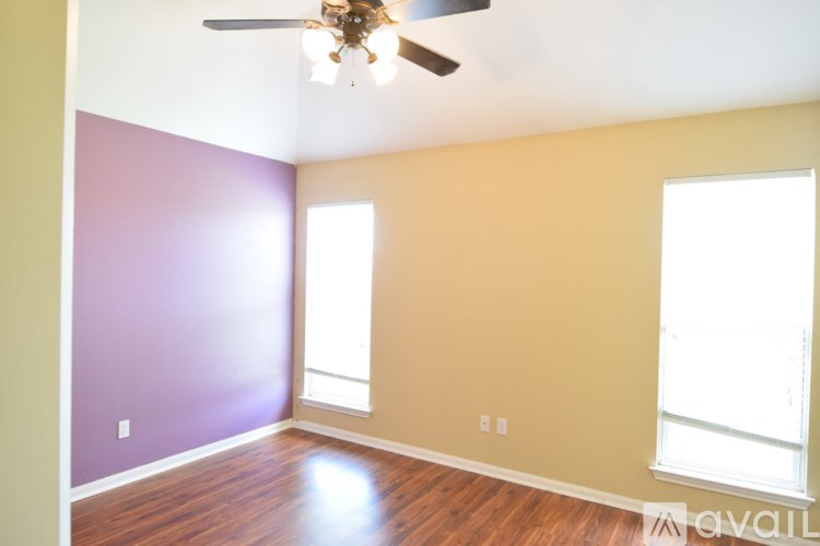 A room with a ceiling fan and two windows.