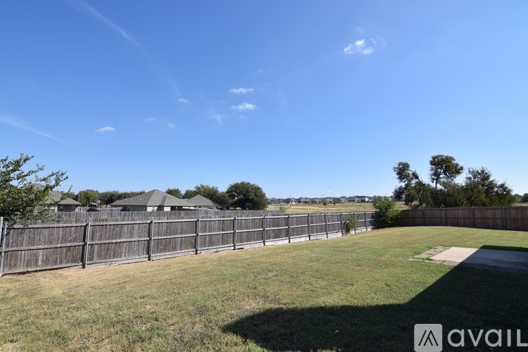 A sunny day in a residential area with houses and a fence.