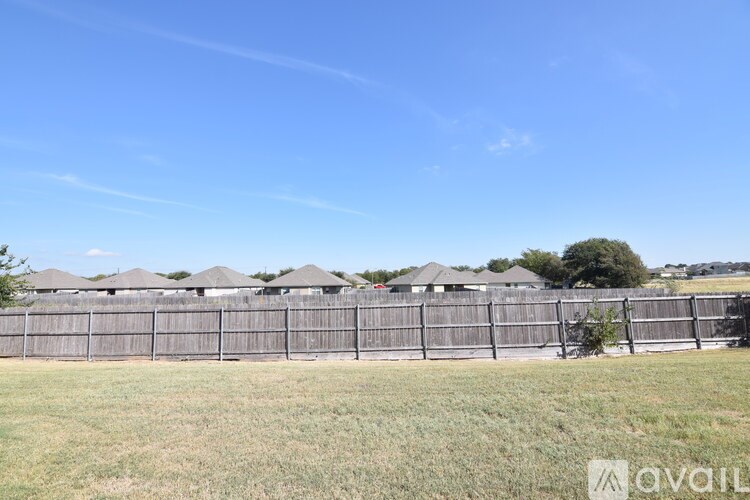 A long fence with a tree in front of it.