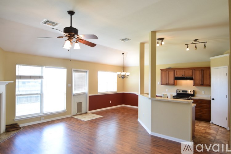 A spacious living room with a ceiling fan and hardwood floors.