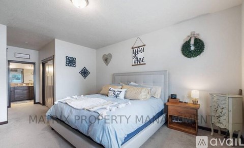 A bedroom with a bed, nightstand, and a wreath on the wall.