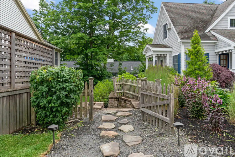 A garden path with a wooden gate leading to a house.