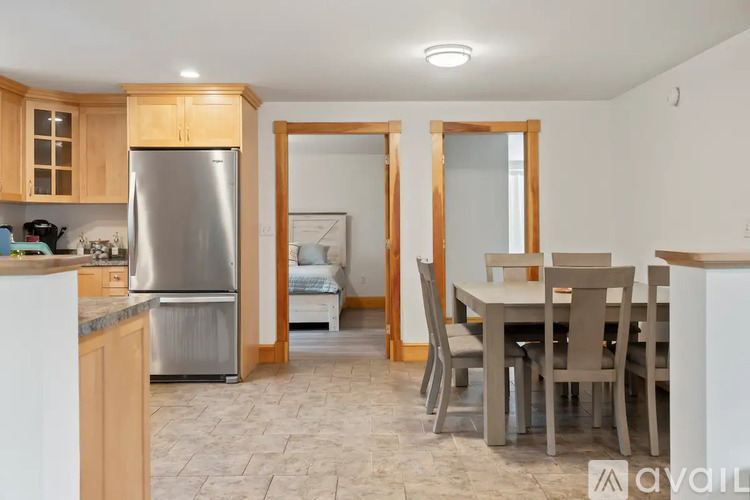 A kitchen with a refrigerator, table and chairs.