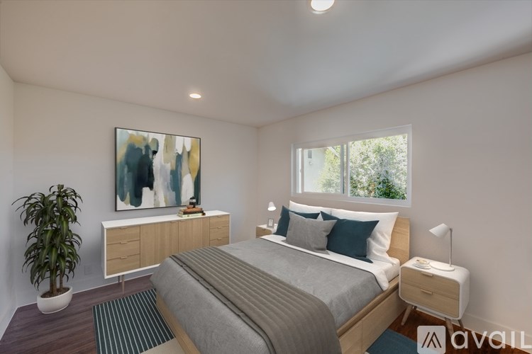 A bedroom with a bed, nightstand, and a painting on the wall.