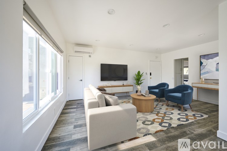A living room with a white couch, a blue chair, and a television.