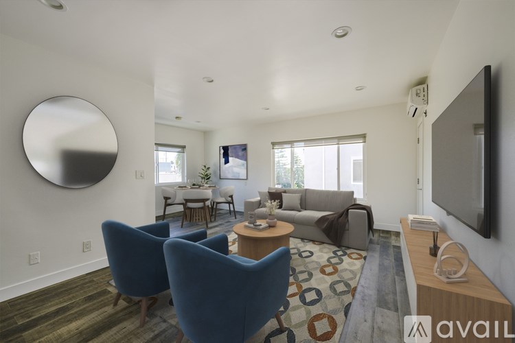 A living room with a blue chair and a television on the wall.