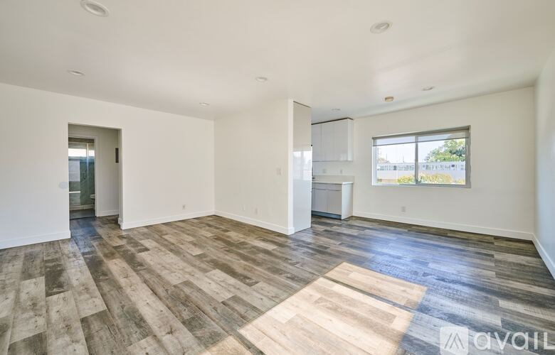 A spacious room with wooden flooring and white walls.