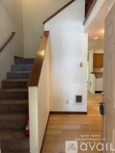 A hallway with a staircase and a door on the right.