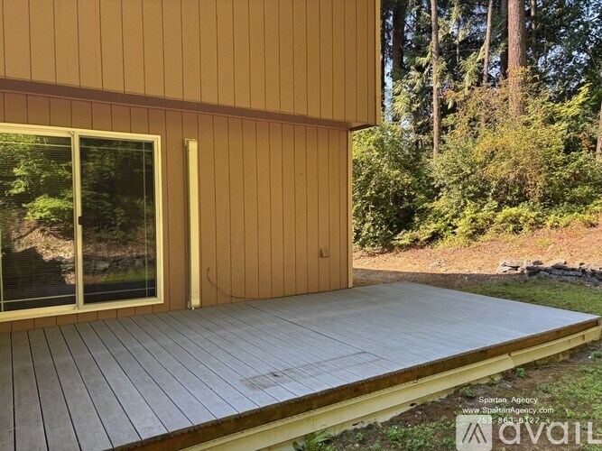 A wooden deck with a sliding glass door is in front of a house.