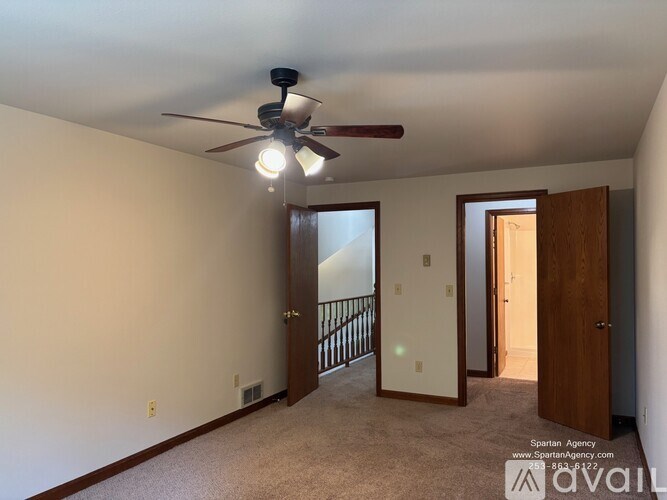 A Spartan Agency image of a carpeted room with a ceiling fan and two doors.