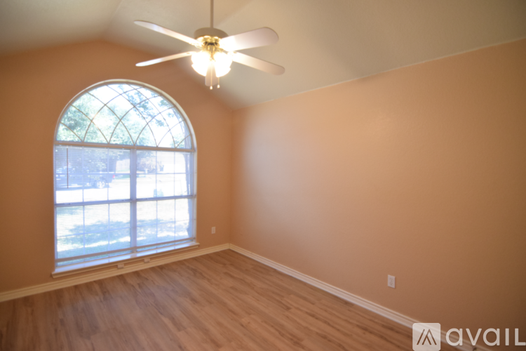 A spacious living room with a fireplace and a ceiling fan.