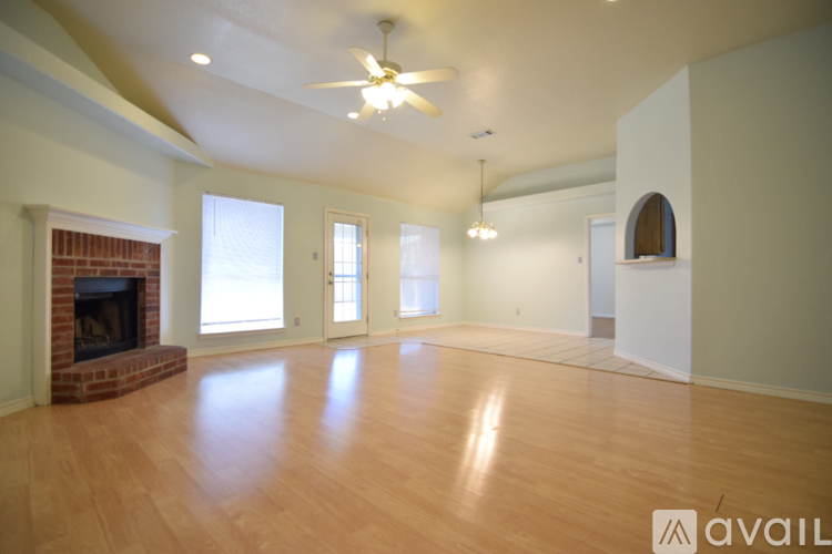 A spacious room with a fireplace and a ceiling fan.