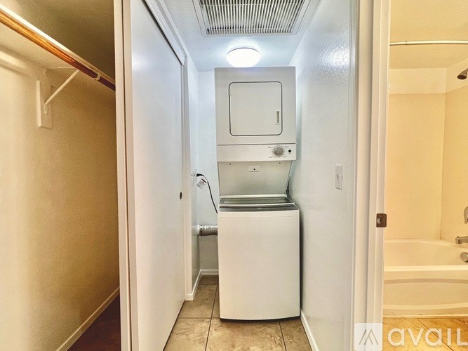 A small, white, compact bathroom with a toilet, sink, and a washer and dryer.
