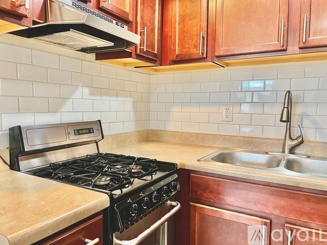 A kitchen with a black stove top oven and a stainless steel sink.