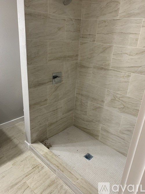 A tiled shower with a drain in the middle.