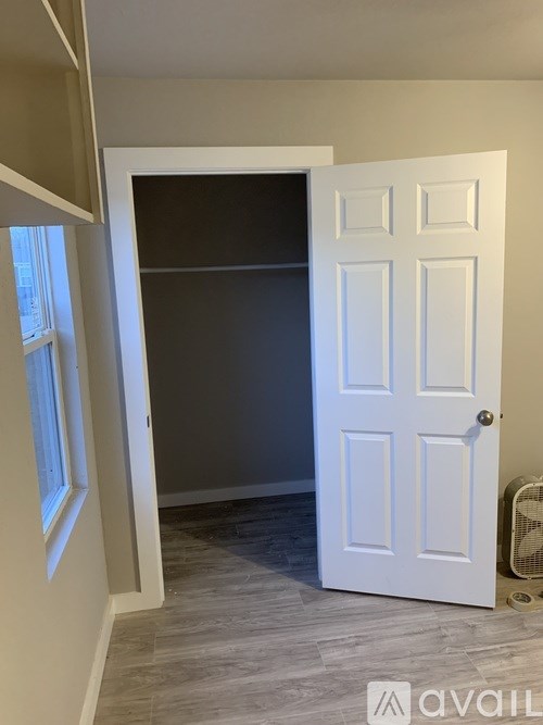 A white door is open to a room with a fan.