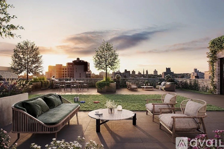 A patio with a table and chairs overlooks a city skyline at sunset.